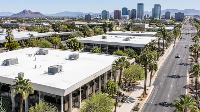 Flat roofs of mid-century low-rise office buildings along a wide avenue in Midtown Phoenix, palm trees, white coated roofs and rooftop units