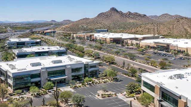Newer suburban office buildings and a shopping center in North Phoenix near the I-17 and Loop 101, flat white roofs, desert hills and saguaros in the distance
