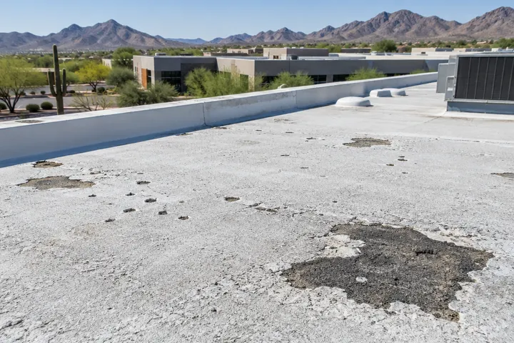 Worn foam roof with the coating eroded, exposed darkened UV-damaged foam spots and small bird pecks