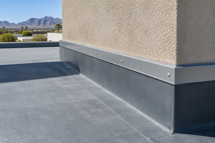 Close-up of a parapet wall base on a flat commercial roof with neat new flashing and termination bar where the roof meets the wall